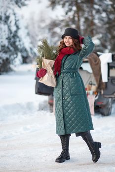 A girl in a winter forest with a paper bag containing spruce branches.