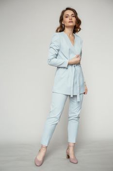 A model in a blue pantsuit on a studio background.