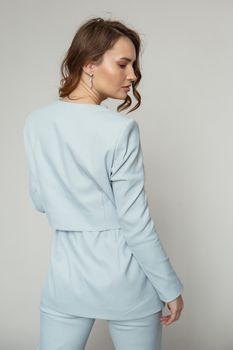 A model in a blue pantsuit on a studio background.