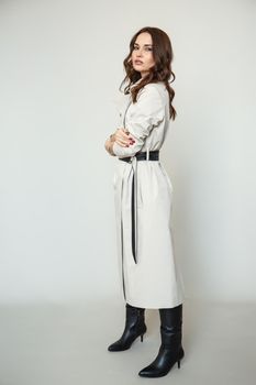 The girl is a model in a coat dress with a leather belt. Studio background.