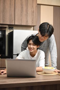 Loving male lgbt couple using laptop computer while spending time together at home. LGBT and love concept.