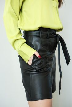 A model in light green clothes and black leather shorts. Shooting fashionable clothes for the showroom.