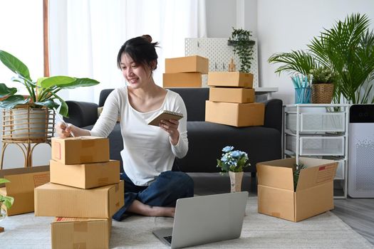 Start up business entrepreneur sitting in modern home office and preparing parcel for delivery. Online selling, E-commerce concept.