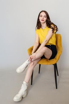 A model girl is standing in a studio with flowers. In the hands of a beautiful girl tulips.