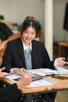 Cheerful young businesswoman having business conversation for project strategy with her colleague in modern office.