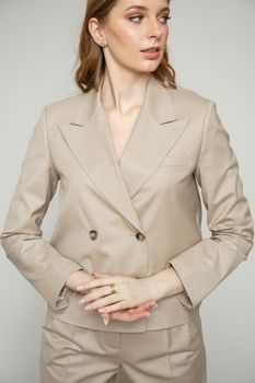 a model in a brown business suit on a studio background.