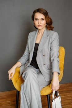 A girl in a business suit, sitting on a chair