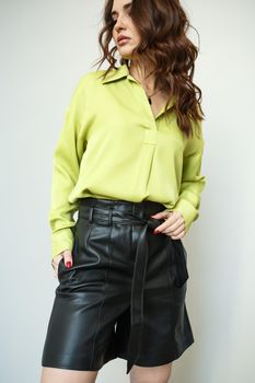 A model in light green clothes and black leather shorts. Shooting fashionable clothes for the showroom.