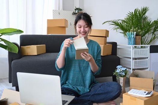 Young woman is working with postal parcel at warehouse for online seller. E-Commerce, online business, online sales concept.