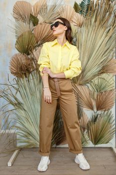 A model girl in a yellow shirt and brown sweatpants is standing in the studio.