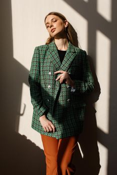 A model girl standing in the rays of the sun. the girl in the reflection of light from the window.