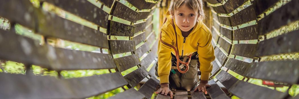 Little boy in a rope park. Active physical recreation of the child in the fresh air in the park. Training for children. BANNER, LONG FORMAT