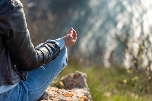 yoga, gesture and healthy lifestyle concept - hand of meditating yogi woman showing gyan mudra over sea sunset background.