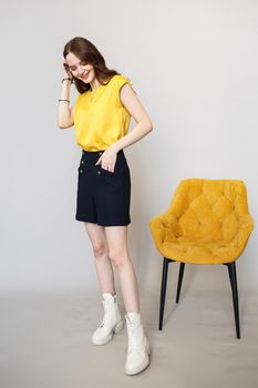 A model girl is standing in a studio with flowers. In the hands of a beautiful girl tulips.