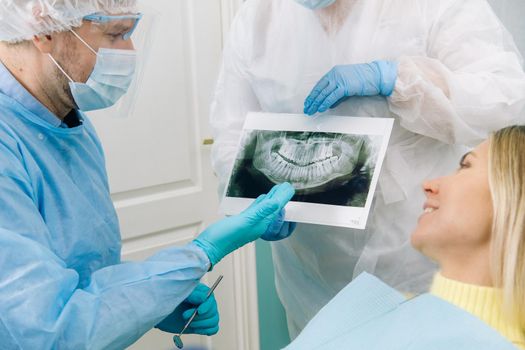 Dentist explaining the details of the X-ray to his patient in the office.