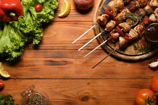 Meat skewers with grilled vegetables on wooden background with copy space for your text.