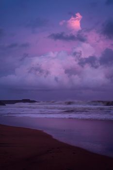 Colorful pinkish purple sunset in the Galle beach, sunlight reflected on the beach waves. Romantic scenery in island of Sri Lanka.