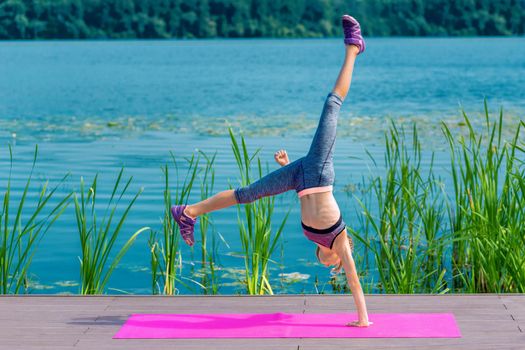 Attractive young sporty little girl is working out by the lake.