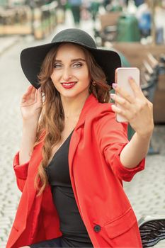 Happy young travel woman is taking selfie on the street of old European city.