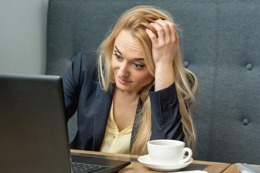 Worried young woman looking surprised while using the laptop at cafe.