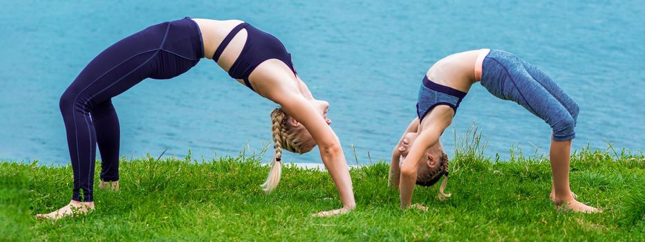 Mother and daughter doing exercise at the shore outdoors. Healthy lifestyle.