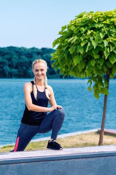 Portrait of woman in sport style clothes by the lake in summer.