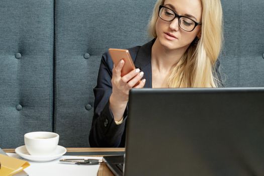 Beautiful young business woman using smartphone at the table in home office.