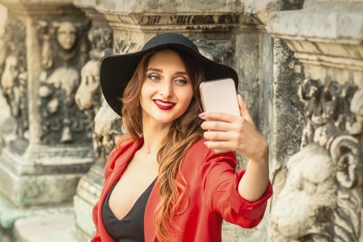 Happy young travel woman is taking selfie on the street of old European city.