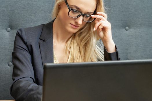 Busy business woman wearing eyeglasses working on laptop at home office.