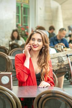 Smiling business woman or student is talking by the phone in outdoor cafe.