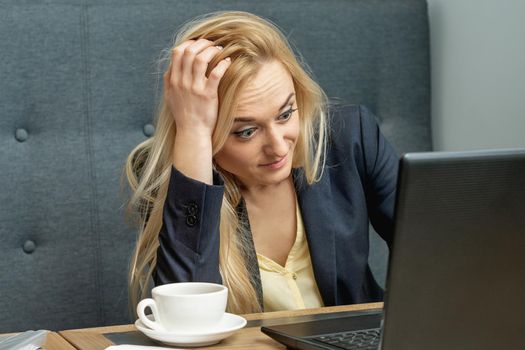 Surprised beautiful young woman looking on a laptop screen at home office.