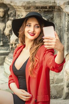 Pretty woman traveler taking selfie portrait by smartphone walking on the city street.