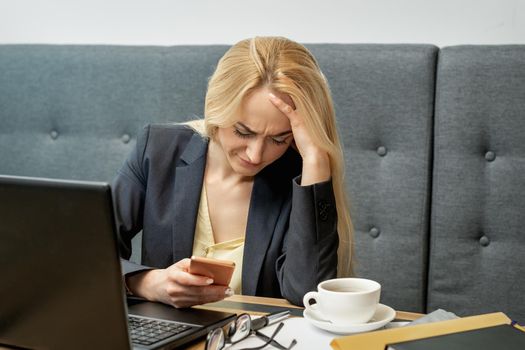 Dissatisfied surprised caucasian young woman look at smartphone screen in the home office.