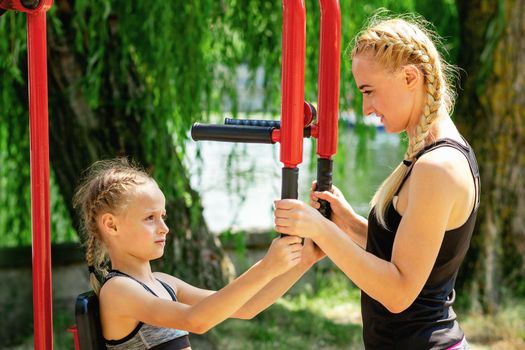 Mom and daughter are engaged in sports simulators in the summer park. Family healthy lifestyle concept.