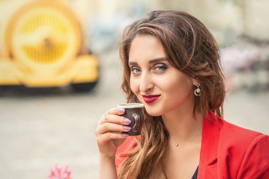 Portrait of young beautiful woman drinking coffee sitting in a cafe outdoors.