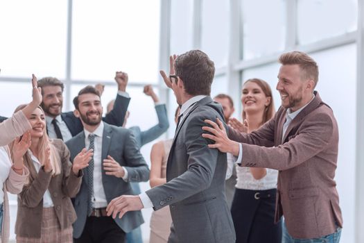 group of cheerful company employees congratulating their colleague. success concept
