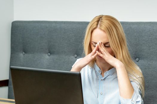 Tired young business woman sitting in front of laptop at office.