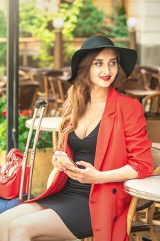 Portrait of young beautiful fashionable brunette woman sitting in outdoor cafe on the street.