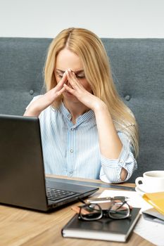 Tired young business woman sitting in front of laptop at office.