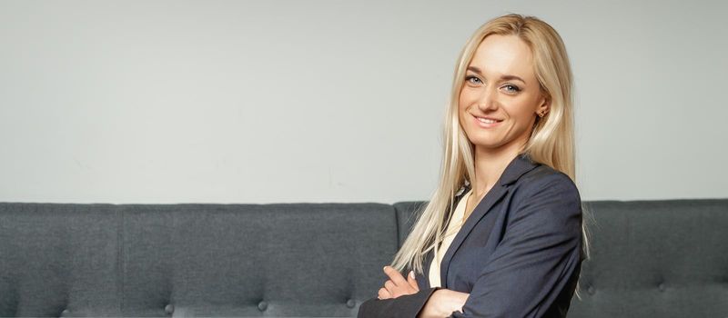 Beautiful caucasian business woman smiling at the camera with folded arms in office.
