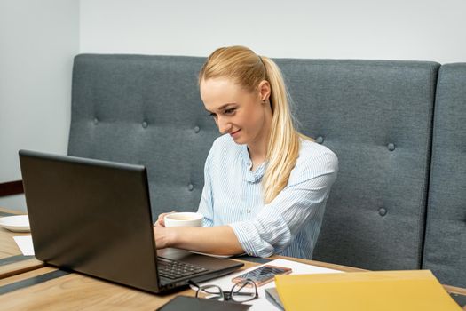 Young woman is using laptop during online learning at home office.