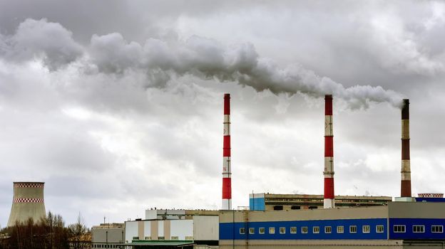 Air pollution from smoke coming from three factory chimneys.