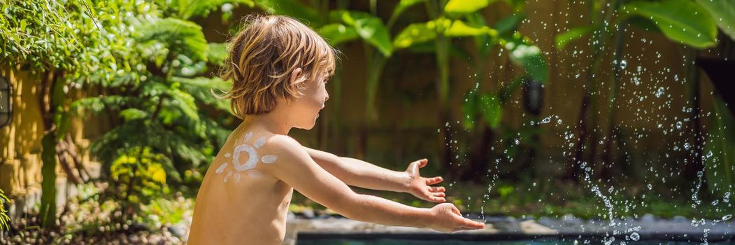 Happy boy with sun painted by sun cream on shoulder playing by the pool. Summer vacation concept. Space for text. BANNER, LONG FORMAT