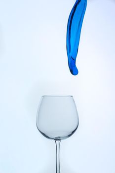 A splash of blue liquid in a glass on a white background. Cutout.