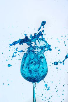 A splash of blue liquid in a glass on a white background. Cutout.