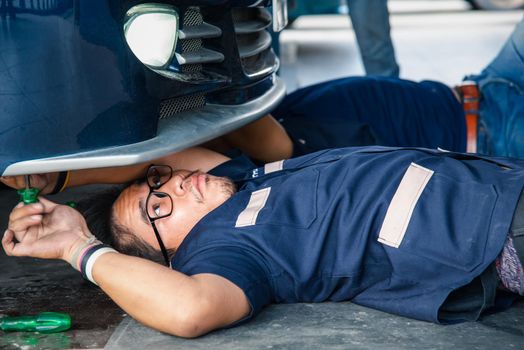 Bangkok, Thailand - May 6, 2017 : Unidentified car mechanic or serviceman checking a car headlight for fix and repair problem at car garage or repair shop