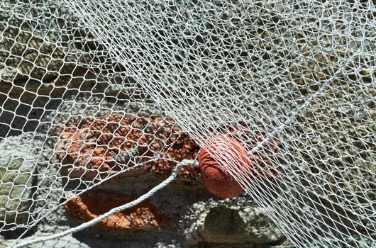 Part of fishing net with orange float hanging  on  the wall , 