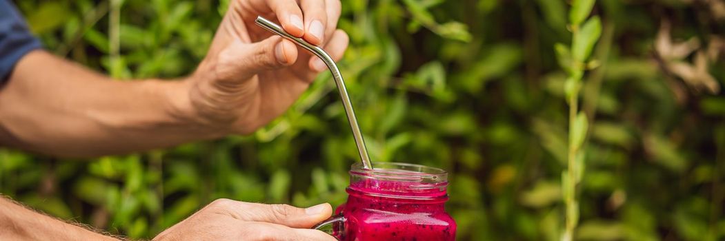 Dragon fruit smoothie with steel drinking straw in male hands. BANNER, LONG FORMAT