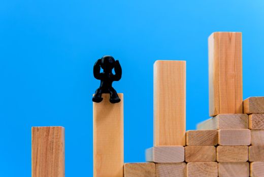 Financial chart made from cubes with a blue background. World market growth rate concept. Black plasticine man is sitting on the chart.