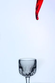 A splash of red wine in a glass on a white background. Cutout.